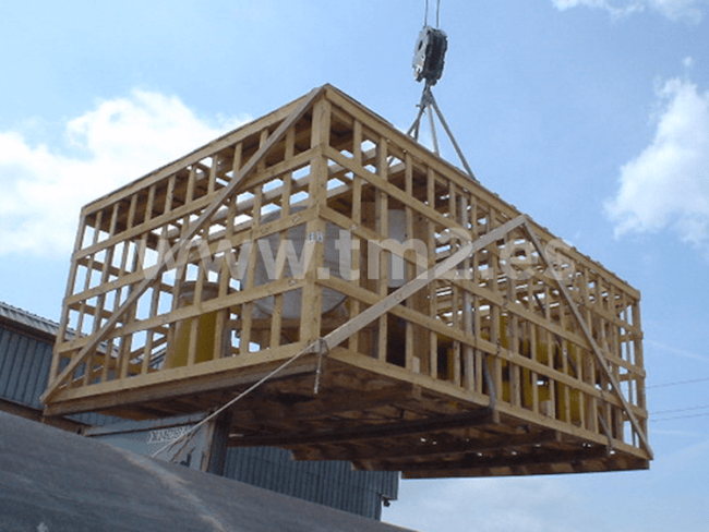 jaula de madera siendo elevada por una grúa