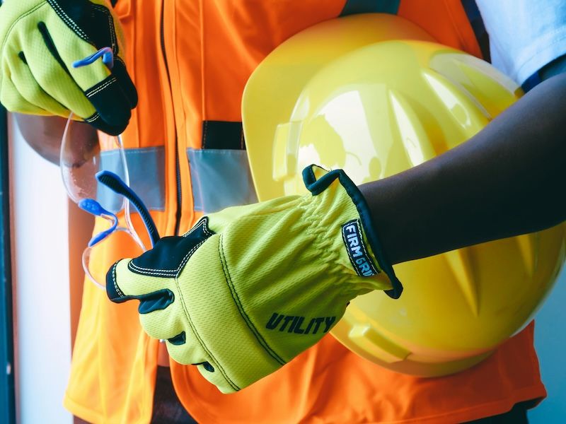 plano detalle de la equipación de seguridad de un trabajador: chaleco, casco, gafas y guantes